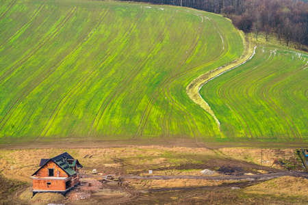 Aerial view of an unfinished house and green empty field in winter among the rural landscape of Lower Silesia, Poland.の写真素材