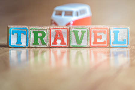 Small toy car on the floor in the living room in the house next to the wooden letter blocks spelling the word travelの写真素材
