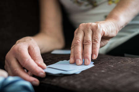 Senior mature woman reaching for the card on top of the deck while playing at home