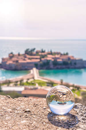 Historical Sveti Stefan old town reflected in large transparent glass ball, coast of Montenegroの写真素材