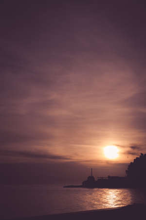 Small sea light marker on a cliff in Petrovac town in Montenegro, photographed at sunset