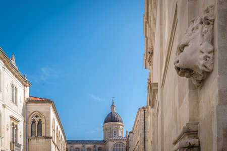 Lion face sculpture on a wall of a building with tall church dome tower in the background, Dubrovnik Old Town, Croatiaの写真素材