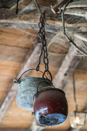Old pots covered in spider web hanging from the ceiling in an old farm buildingの写真素材