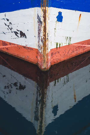 Water reflection of a front of a small empty fisherman boat moored in portの写真素材