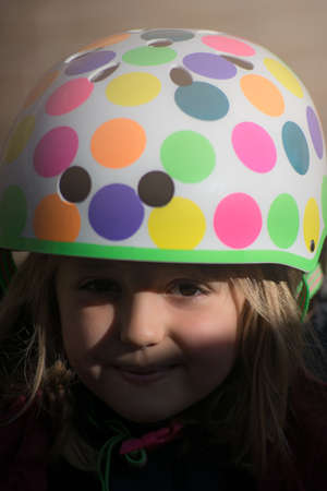 Portrait of a young Caucasian little girl wearing small colorful cycling helmet