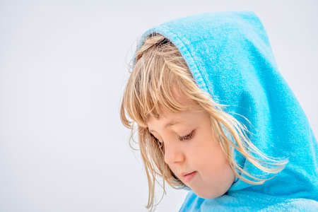 Portrait of cute little Caucasian girl wrapped in towel after bath and standing at beach in summerの写真素材