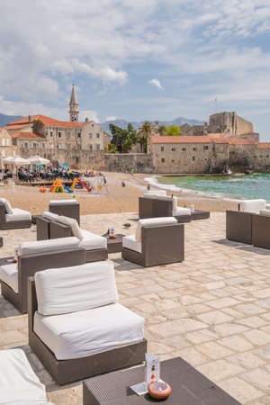 Budva, Montenegro - April 2018 : Large empty lounge chairs waiting for tourists on the beach outside a cafe and restaurantのeditorial素材