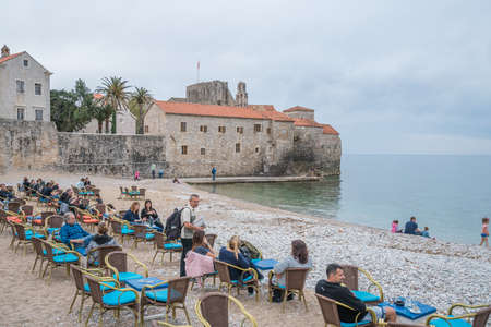 Budva, Montenegro - April 2018 : Tourists sitting on  chairs on the beach outside a cafe, enjoying coffee, refreshments and dessertsのeditorial素材