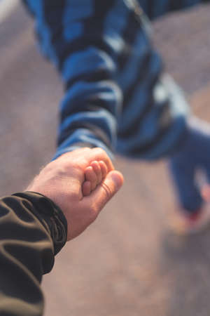 Little boy walking together with his father and holding his hand