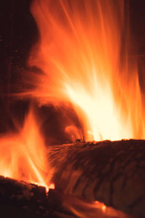 Long exposure image of the large piece of firewood burning in hot flames inside the fire place at...