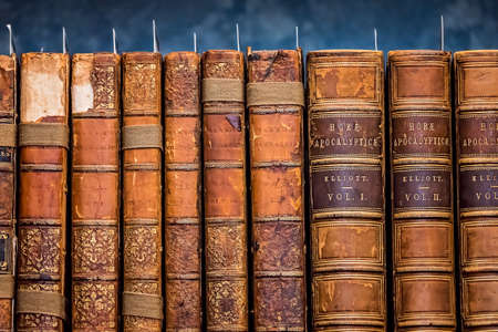 Row of antique hard and softcover books on shelf in a libraryのeditorial素材