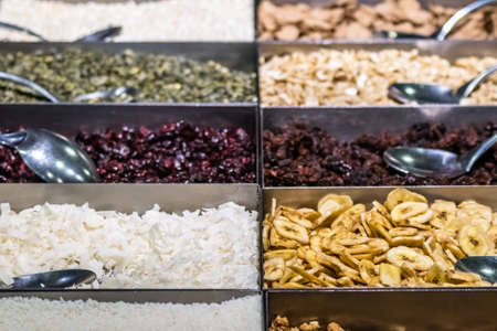 Trays with dehydrated fruits including raisins and pieces of coconut and banana on sale in the...