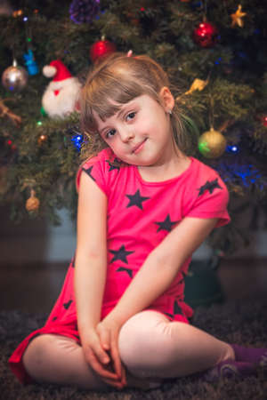 Cute Christmas girl with the Christmas tree lights bokeh in the backgroundの写真素材