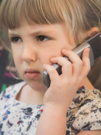 Cute little Caucasian girl talking on the mobile phone while sitting in the train carriageの写真素材