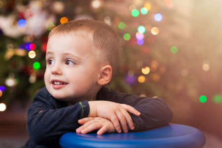 Happy and smiling cute Caucasian boy portrait with the Christmas tree in the background