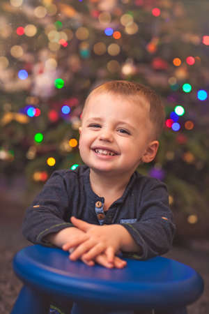 Happy and smiling cute Caucasian boy portrait with the Christmas tree in the backgroundの写真素材