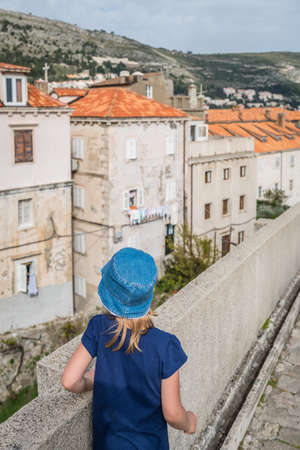 Little girl wearnig blue hat walking on the historical walls of the Old Town in Dubrovnik, Croatiaの写真素材