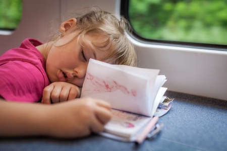 Little Caucasian girl asleep inside the train carriage on their trip back home