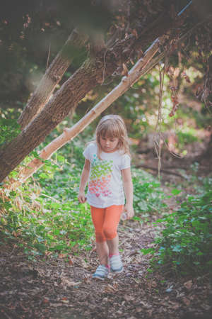 Young Caucasian girl walking on a narrow path in a forestの写真素材