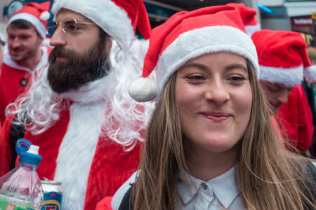 London, UK - December 2018 :Happy smiling girl dressed in santa outfit and taking part in a themed SantaCon eventのeditorial素材