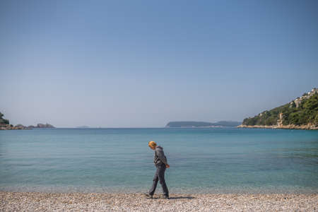 Blond Caucasian female tourist walking slowly on the beach and admiring the stunning Croatian coast in Dubrovnikの写真素材