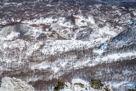 Winter landscape of trees and hills in snow as seen from the top of Mount Lovcen in Lovcen National...