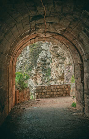 Tunnel cut out in the seaside rocky cliffs on the walking path in Petrovac bay, on the coast in Montenegroの写真素材