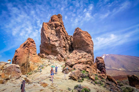Tenerife, Spain - April 2013 : Tourists on a walking path going to the strangely shaped rock formations with The Teide volcano, spanish highest mountain, in the background, Canary Islandsのeditorial素材