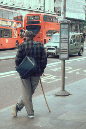 London, England - December 2018 : Elderly men with a walking stick waiting for bus on the bus stop in Brixtonのeditorial素材