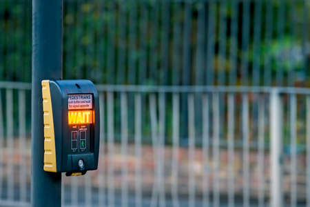 Pedestrian button with wait signal lit up at a pedestrian crossing in London, UK