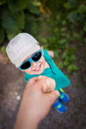 Cute little Caucasian boy wearing sunglasses holding his father handの写真素材