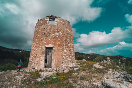 Young girl running towards the remnants of an old windmill in Askos, Zakynthos island, Greeceの写真素材