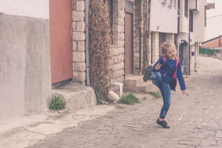 Little girl having fun practising kicks on a street in Ohrid, Northern Macedoniaの写真素材