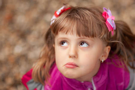 Portrait of a cute Caucasian girl making grumpy face wearing pink hairclips and fleece