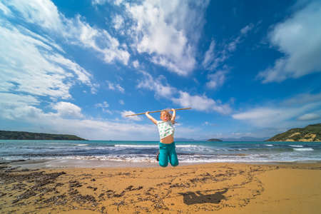 The girl training martial arts with the long wooden stick on the beach in summerの写真素材