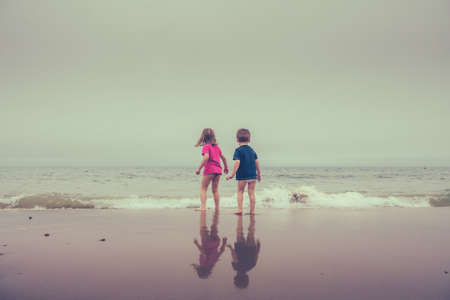 Little boy and girl standing in the sea waters on the beach in summerの写真素材