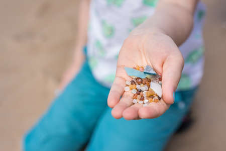 Little girl holding small tiny harmful plastic microbeads collected on the beach in Zante, Zakynthos, Greeceの写真素材