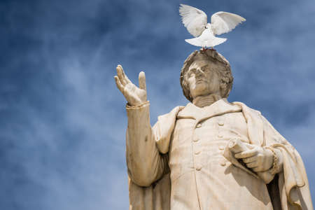White bird sitting on top of ancient statue of Dionysios Solomos in Zakythos Town square, Greeceの写真素材