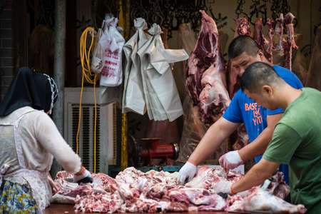 Xian, China -  July 2019 : Two men workers cutting and segregating lamb and cow carcass meat and bones, the street food vendors in the Muslim quarter of Xian town, Shaanxi Provinceのeditorial素材