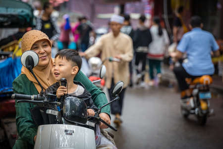 Xian, China -  July 2019 : Muslim woman with her son sitting on a scooter on the road in the Muslim Quarterのeditorial素材