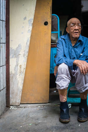 Xian, China -  July 2019 : Very old man with wrinkled face sitting on a trolley in front of a small stall in Muslim Quarterのeditorial素材