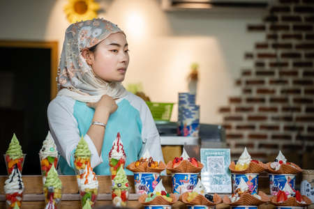 Xian, China -  July 2019 : Muslim woman selling ice cream like dessert with pieces of fresh fruits...