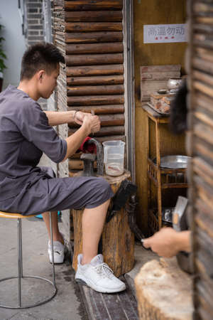 Xian, China -  July 2019 : Man using hammer to make crafts on the street market in the Muslim...