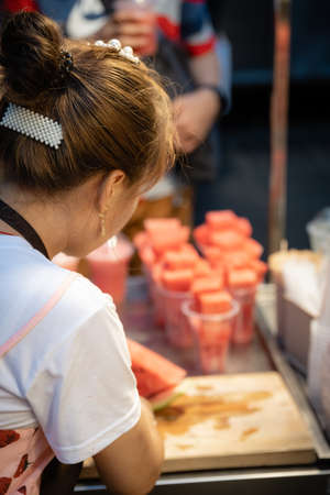 Xian, China -  July 2019 : Woman cutting watermelon into small pieces to be sold in plastic cups or blended for juice in a stall in Muslim Quarterのeditorial素材