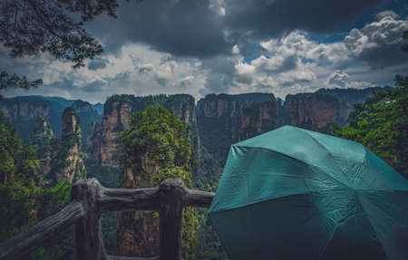 Tourist holding green umbrella admiring the view and  on the scenic viewpoint, Avatar mountains nature park, Zhangjiajie, Chinaの写真素材