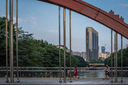 Chengdu, China - July  2019 : People walking across the arched steel bridge in Chengdu city, Sichuan...