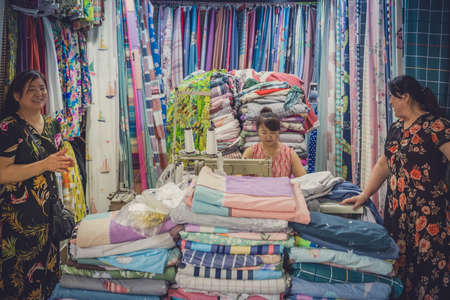 Chengdu, China -  July 2019 : Chinese woman standing in front of the small textile and tailoring shopのeditorial素材