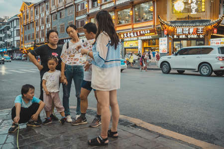 Wulingyuan, China - August 2019 : Chinese family standing outside restaurant and deliberating over...