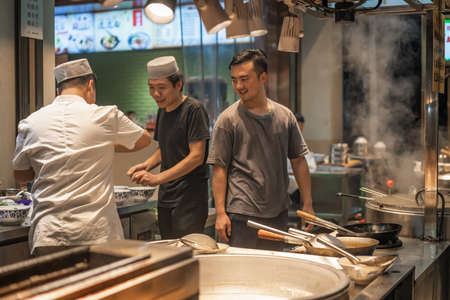 Xian, China -  August 2019 :  Chinese chefs playing around and having fun while not preparing food in a small restaurant on the street in the Muslim Quarterのeditorial素材