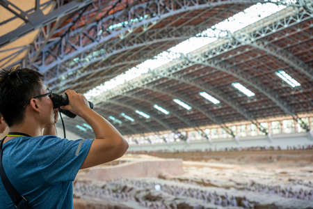 Xian, China -  July 2019 : Chinese tourist looking through the binoculars at the Terracota Army, Xian, Shaanxi Provinceのeditorial素材